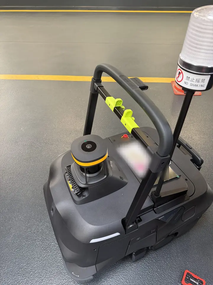 Pudu MT1 Max Kehrroboter von schräg hinten mit Schiebegriff, 3D-LiDAR-Sensor und Warnleuchte in einer Halle